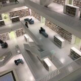 A multi-level library interior with modern architecture, bookshelves, and minimalistic white design.