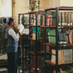 A woman exploring bookcases in a classic library setting, immersed in reading.