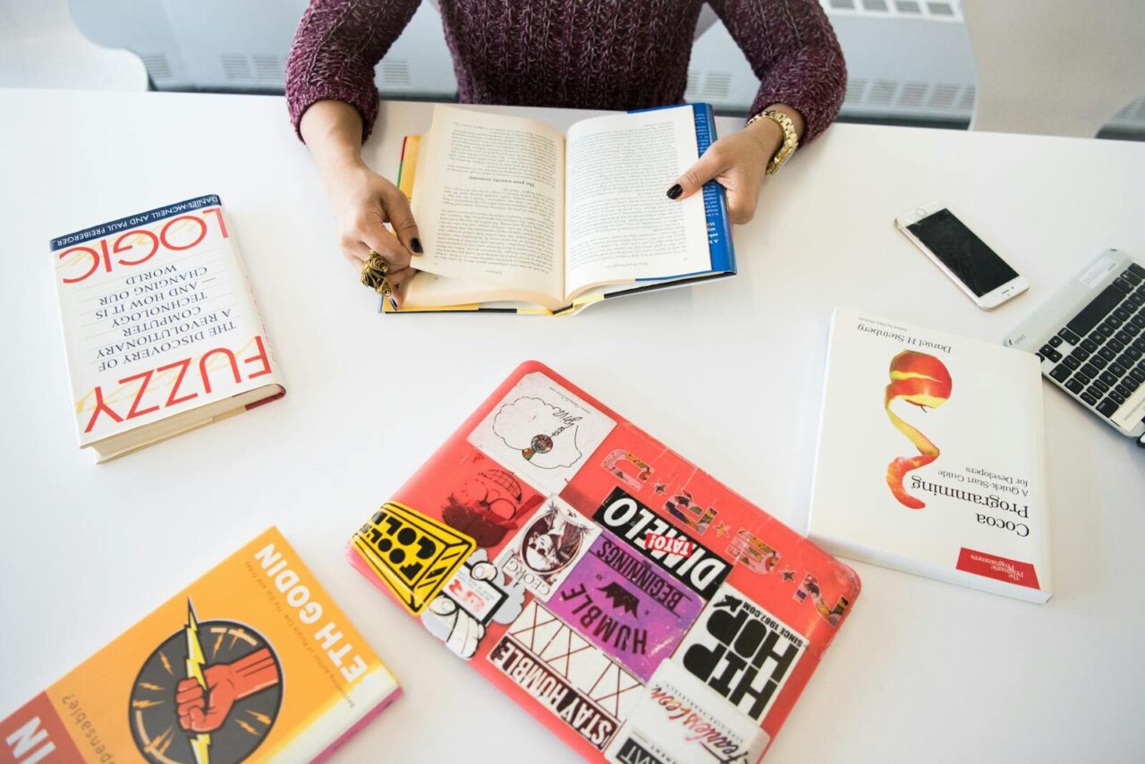 Overhead view of a workplace desk with books, a laptop, and technology essentials.