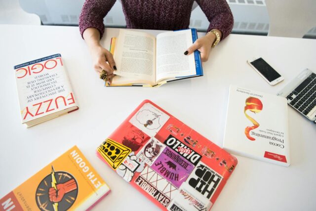 Overhead view of a workplace desk with books, a laptop, and technology essentials.