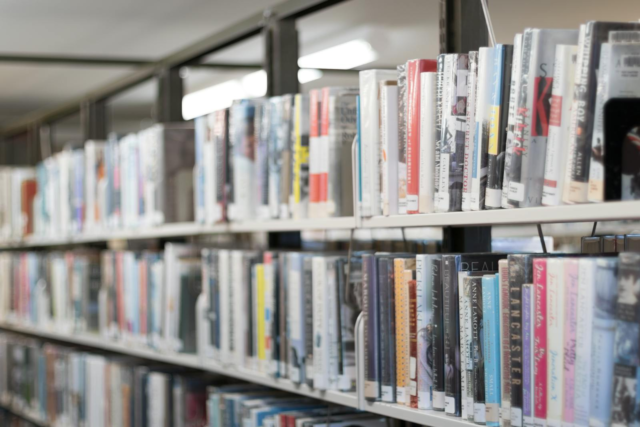 Rows of colorful books on shelves in a well-lit library in West Hartford, CT.