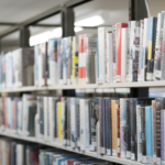 Rows of colorful books on shelves in a well-lit library in West Hartford, CT.