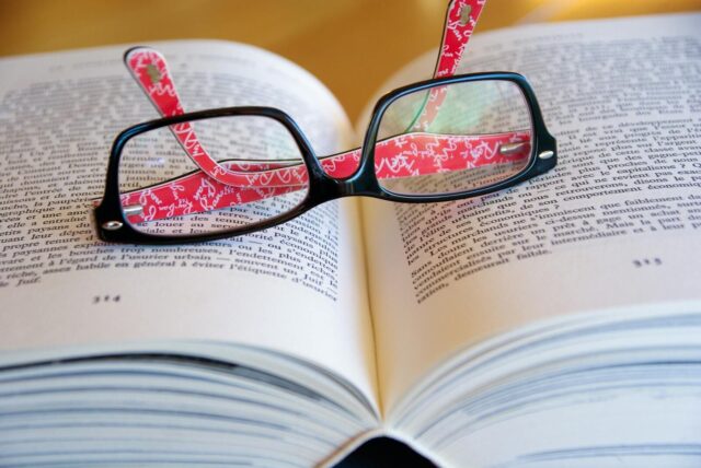 Eyeglasses resting on an open book reflecting text for a concept of literature and learning.