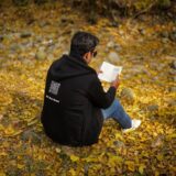 A man reading a book on fallen autumn leaves in New Theed, Kashmir.