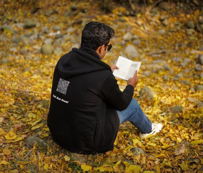 A man reading a book on fallen autumn leaves in New Theed, Kashmir.