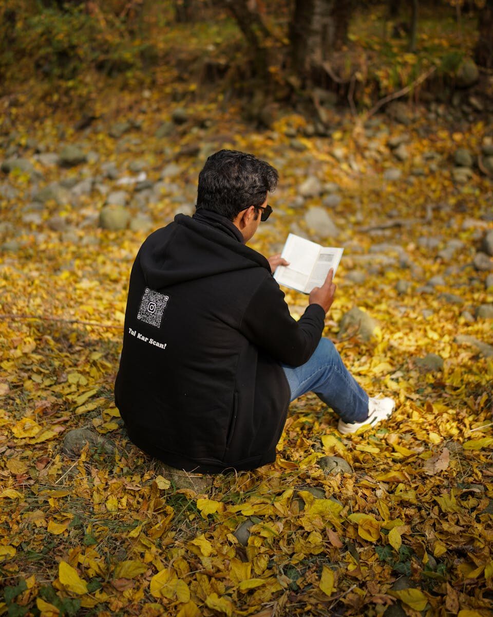 A man reading a book on fallen autumn leaves in New Theed, Kashmir.