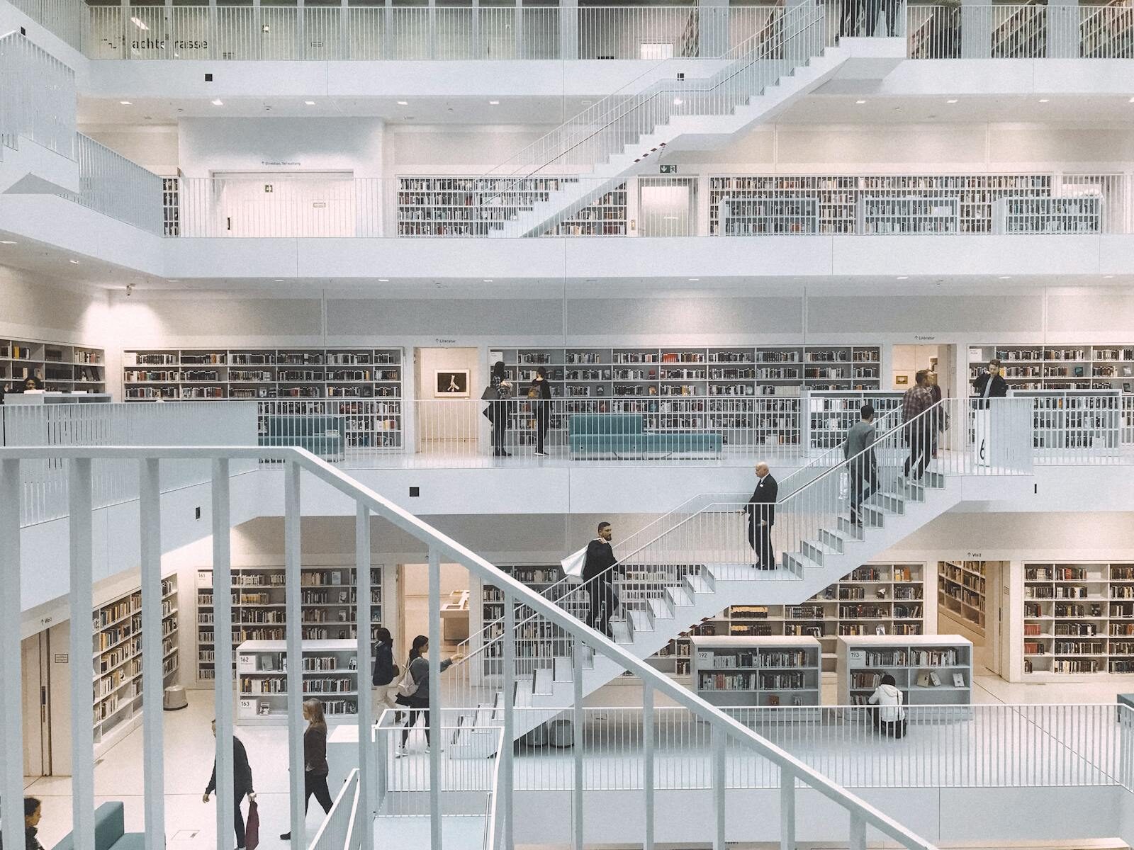 Spacious and minimalist design of the Stuttgart City Library showcasing multiple levels of books and people.