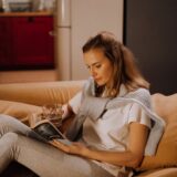 Woman reading a book on a cozy couch in a warm, inviting living room.