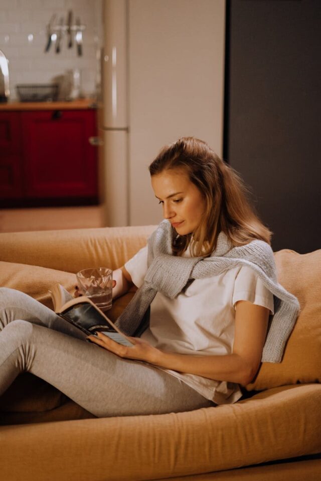 Woman reading a book on a cozy couch in a warm, inviting living room.