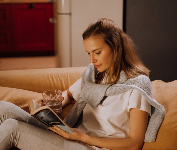 Woman reading a book on a cozy couch in a warm, inviting living room.