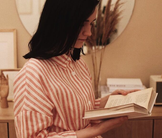 A woman enjoys a quiet moment reading a book at home, offering a serene and contemplative mood.