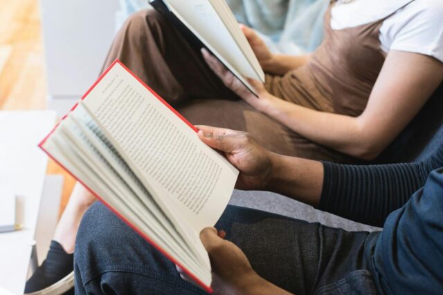 Two students reading books indoors, focused on learning and knowledge.