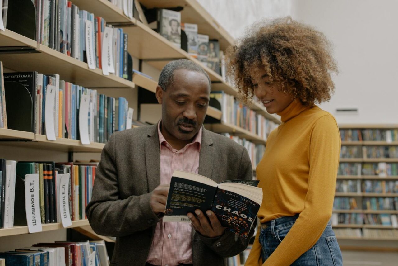 A man and a woman studying together in a modern library setting, focusing on learning and education.