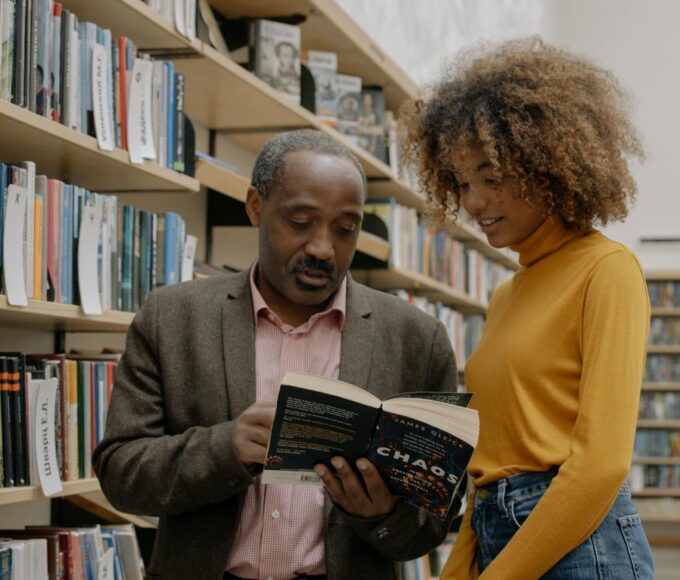 A man and a woman studying together in a modern library setting, focusing on learning and education.