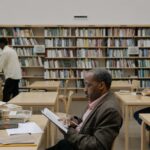 Adults reading and studying in a bright, modern library with a focus on education and diversity.