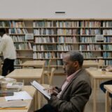 Adults reading and studying in a bright, modern library with a focus on education and diversity.