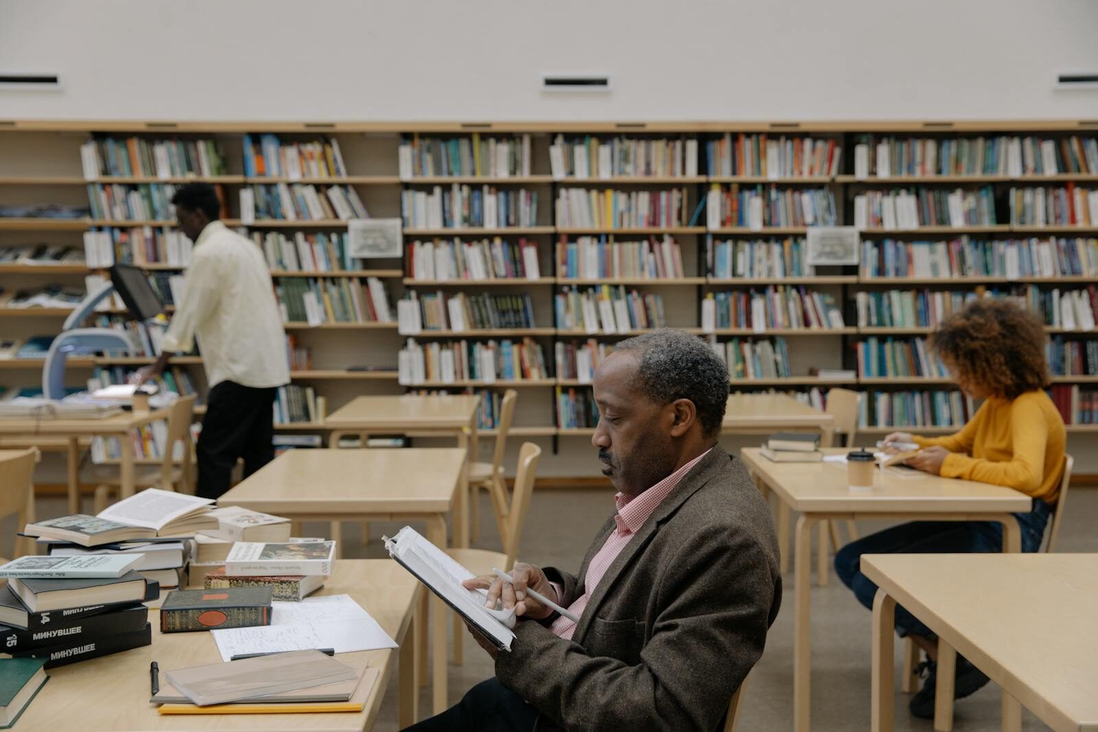 Adults reading and studying in a bright, modern library with a focus on education and diversity.