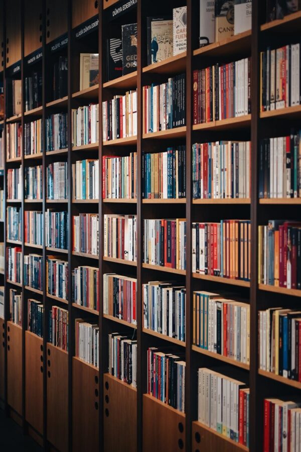 Vertical shot of wooden bookshelves in a cozy bookstore, showcasing a diverse range of books indoors.