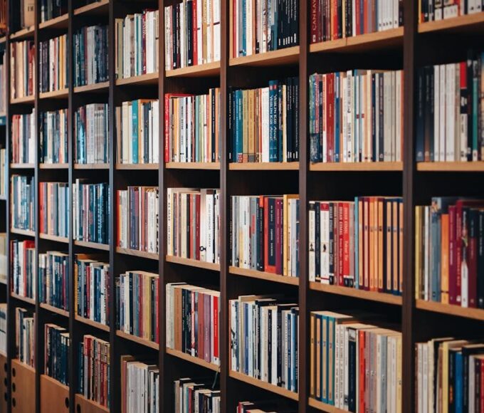 Vertical shot of wooden bookshelves in a cozy bookstore, showcasing a diverse range of books indoors.