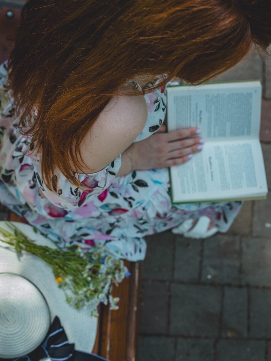 a woman with red hair is reading a book