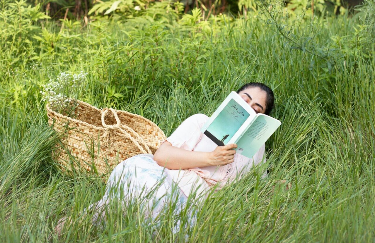 A woman laying in the grass reading a book