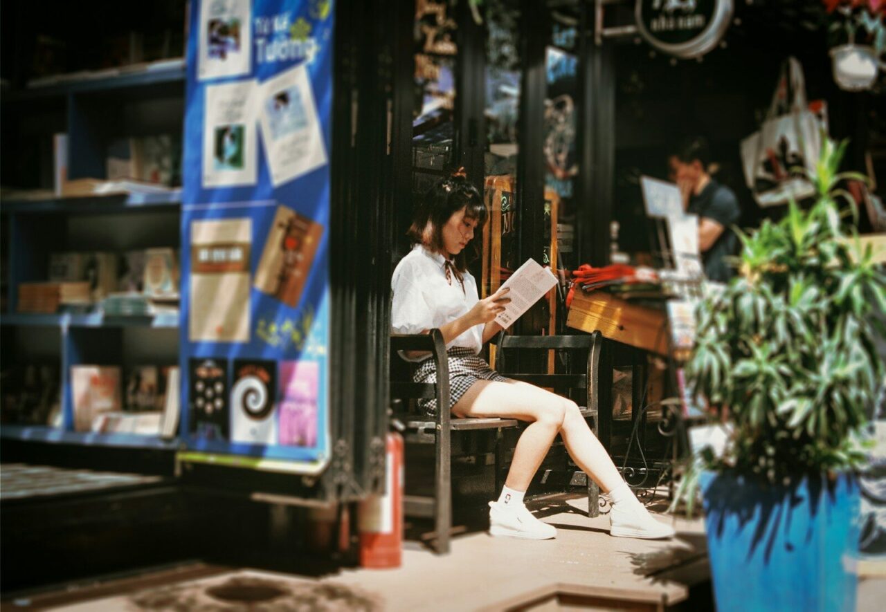 woman reading book sitting on bench