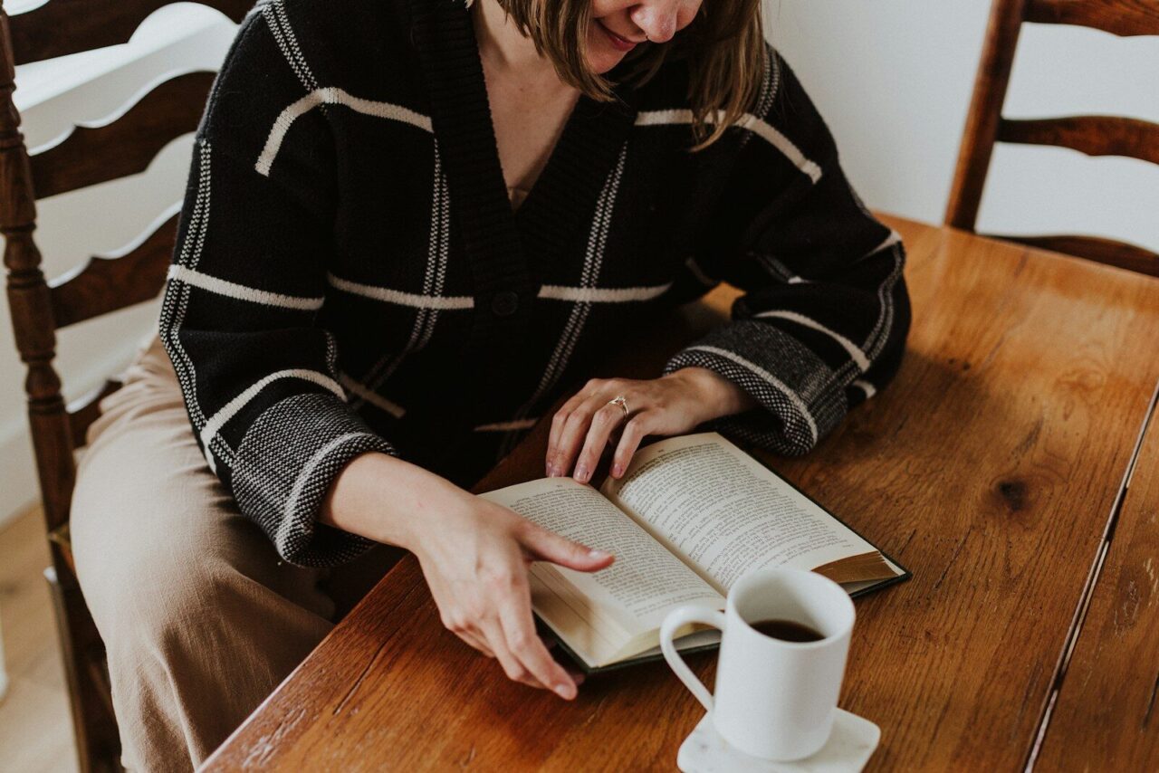 A woman sitting at a table reading a book