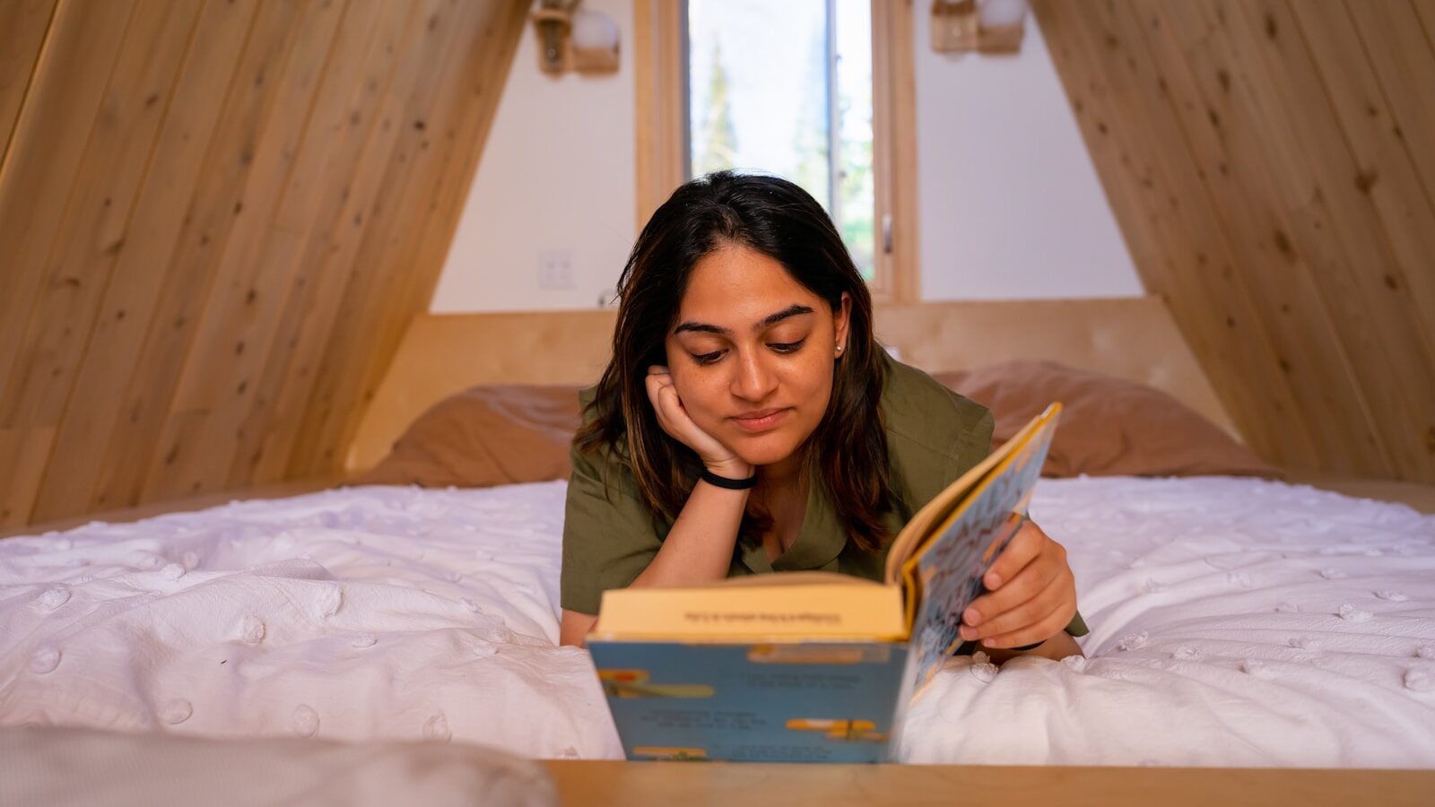 a woman laying on a bed reading a book